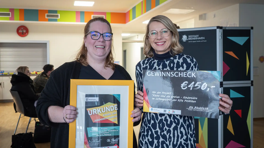 Das Foto zeigt zwei Frauen. Sie halten einen Gewinnscheck und eine Urkunde in ihren Händen.